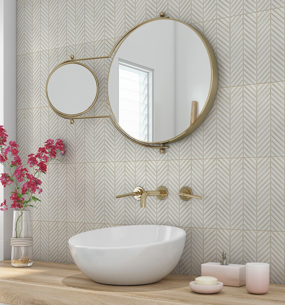 <img src=“Juyu-mockup-Bath-Wall_web-1.jpg” alt=“Bathroom sink with gold faucet and circular mirror, Juyu mosaic tile on wall”/>